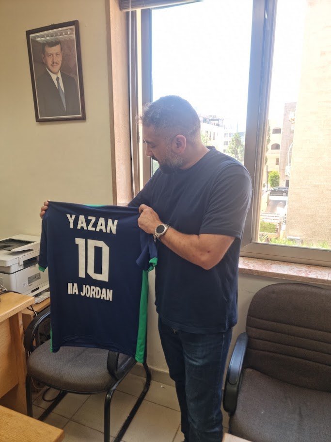 Yazan Ibrahim holding an IIA Jordan jersey with his name and the number 10